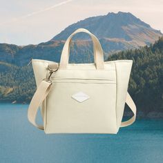 a white bag hanging from the side of a lake with trees in the background and mountains in the distance