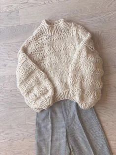 two sweaters and pants sitting on top of a wooden floor