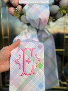 a person holding up a pink monogrammed tie with the letter e on it