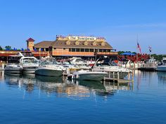 several boats are docked in the water near a building and pier with a sign that says the boathouse