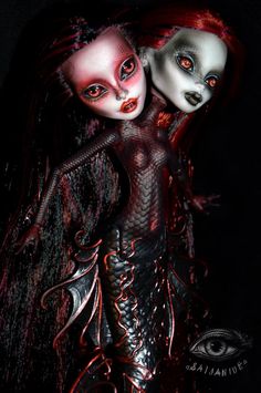 two dolls with red hair and white makeup are standing next to each other in the dark