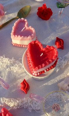 two heart shaped cakes sitting on top of a table next to wine glasses and spoons