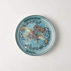 a blue plate with an elephant on it sitting on a white table top next to a wall