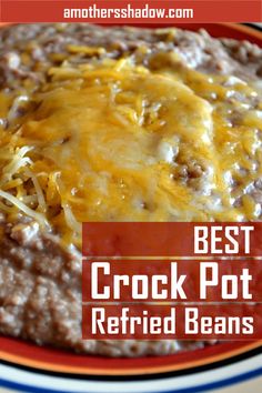 the best crock pot refried beans recipe is in a bowl with cheese on top