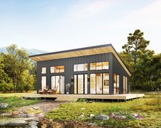 a small black house sitting on top of a lush green field next to a lake