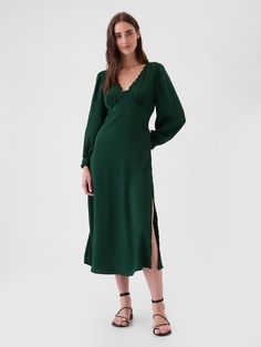 Soft satin midi dress.  Lace-trim V-neck.  Long sleeves.  Empire waist.  Slit at the hem.  Fit: Slim.  An A-line silhouette that sits close to the body with a flared opening.  Hits below the knee.  Models wearing Gap 70s Housewife Fashion, Long Sleeve Wedding Guest Dress Fall, Green V-neck Maxi Dress For Winter, Christmas Party Dress Work, Green Silk Long Sleeve Midi Dress, Green Long Sleeve Satin Midi Dress, Winter Wedding Dress Guest, Chic Green V-neck Long Sleeve Dress, Green Relaxed Fit V-neck Midi Dress