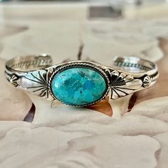 "Genuine Turquoise Kingman Mohave Bracelet 925 Silver Turquoise Cuff.  She is so pretty.  Gorgeous turquoise color.  All bezel set in 925 Silver with beautiful intricate silver work surrounding the stone on both sides.  Rope design going down the shaft of the cuff...beautiful flower design on both side of stone. * Genuine Kingman Turquoise * Due to the nature of turquoise variations in colors/shades/matrix are all different.  But every bracelet is beautiful. * Handcrafted and Hallmarked 925 Ster Ranch Logo, Jewlery Rings, Turquoise Bracelets, Turquoise Jewellery, Beautiful Flower Designs, Colors Shades, Turquoise Cuff, Rope Design, Black Gift Boxes