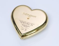 Yves Saint Laurent Heart Compact Limited edition YSL gold tone "jewel powder" compact. Brand new and unopened heart compact with dark green heart-shaped crystal. Comes with box. Approximate Measurements: Length 2.5”, Width 2.6” Made in: France Condition: Brand New Green Wishlist, Ysl Gold, Ysl Beauty, Vintage Cosmetics, Powder Compact, Green Heart, Creative Tattoos, Girly Jewelry, Compact Mirror