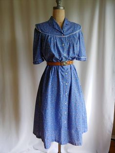 "Iconic 70s dress both in colours and style Lightweight cotton fabric suitable for summer Smocked shirtdress style that could work as a robe or light jacket Pockets in the side seams ** Hand tooled 70s belt is not included but can be found in the shop here: https://www.etsy.com/ca/listing/828864959/70s-hand-tooled-western-belt-tooled?ref=shop_home_active_29&pro=1 Label - Pia and Paula EU 38 UK 12 US 10 (shown on a size 6 mannequin) Bust - 36\" Back - 12\" (quite narrow) Sleeve - 13\" Length Spring Cotton Shirt Dress With Spread Collar, Knee-length Cotton Shirt Dress With Placket, Cotton Shirt Dress With Placket For Spring, Cotton Knee-length Shirt Dress With Placket, Vintage Cotton Dress For Summer, Summer Cotton Shirt Dress With Buttons, Cotton Shirt Dress With Pockets, Cotton Prairie Dress For Garden Party, Cotton Daywear Dresses With Buttons