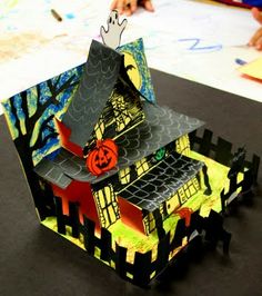 a house made out of construction paper with a ghost on the roof