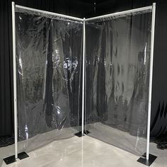 two clear partitions in the middle of a room with black curtains on them and one closed