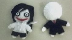 two small stuffed dolls sitting next to each other on a white surface, one with black hair and the other with red eyes