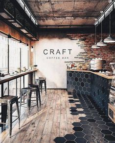 the interior of a restaurant with wooden floors and brick walls, an open kitchen area