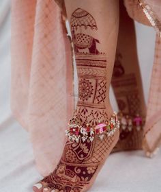 the legs and feet of a woman with henna tattoos on their feet, decorated with jewels