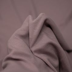 an unmade bed with a purple blanket on it's side and the sheets pulled back