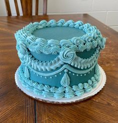 a blue cake sitting on top of a wooden table