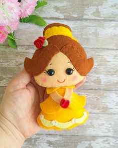 a hand holding a small felt toy with a princess on it