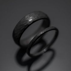 two black rings sitting next to each other on top of a gray surface with one ring in the middle