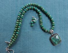 This 20 inch necklace is made from faceted green turquoise 8 mm beads and green Czech 6 mm beads. It has a silver hook and eye and a sterling silver pendant. The African turquoise pendant measures about 1 1/4 inch by 1 1/4 inch. It has .925 stamped on the back. The pendant has several shades of green with black matrix in it. The matching earrings are included in the set. Green Turquoise Necklace With Faceted Beads As Gift, Green Turquoise Round Bead Necklace In Sterling Silver, Green Turquoise Round Beads Necklace In Sterling Silver, Green Turquoise Beaded Necklace In Sterling Silver, Turquoise Necklace For Jewelry Making With Chrysocolla, Green Turquoise Necklace With Sterling Silver Gemstone Beads, Green Turquoise Gemstone Beads Necklace In Sterling Silver, Green Turquoise Necklace With Round Beads In Sterling Silver, Green Turquoise Necklace With Sterling Silver