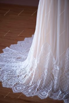 the back of a white wedding dress on a wooden floor with lace overlays