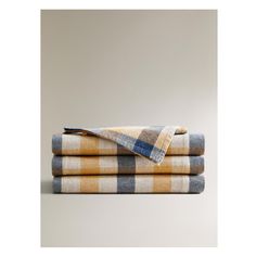 three yellow and blue checkered towels folded on top of each other in front of a gray wall