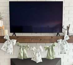 a flat screen tv mounted on the wall above a mantle with bow ties hanging from it