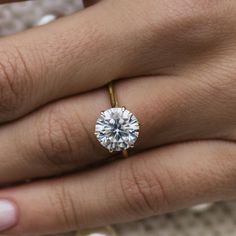 a close up of a person's hand with a diamond ring on their finger