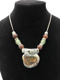 A nice thick piece of glass found in Sri Lanka is framed in patinaed and painted resin.  African glass beads and patinaed metal beads are strong on a double nickel free chain Each Wearable Slip piece is a unique work of art created  and signed by Fredian Slips Artisan Metal Necklace With Patina, Artisan Metal Necklaces With Patina, Artisan Soldered Round Beads Jewelry, Bohemian Silver Resin Jewelry, Unique Silver Necklace With Patina, Unique Patina Jewelry With Round Pendant, Unique Pendant Necklace With Patina, Unique Round Pendant Jewelry With Patina, Unique Patina Round Pendant Necklace