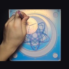 a person is drawing on a piece of paper with blue and white circles around it