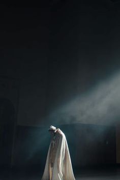 a woman in white dress standing on stage with light streaming through her face and head