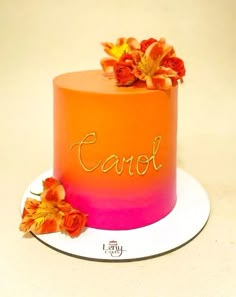 an orange and pink cake sitting on top of a white plate next to some flowers