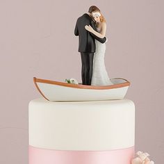 a wedding cake with a bride and groom figurine on top, in the shape of a boat