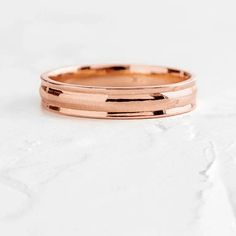 a rose gold wedding band on top of a white surface