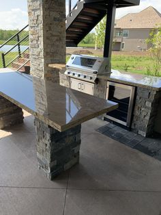 an outdoor kitchen with stone pillars and grill