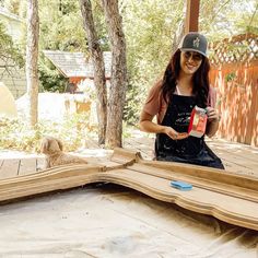 a woman sitting on top of a wooden floor next to a tree filled with leaves