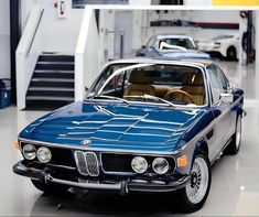 a blue car parked in a garage next to another car and some stairs on the other side