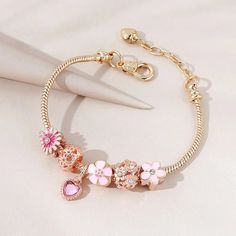 LOVCIA Pink Floral Daisy Love Fashion Bracelet for Women Enhance your jewelry collection with the LOVCIA Pink Floral Daisy Love Fashion Bracelet. This elegant bracelet features a blend of pink floral daisy charms, a heart charm, and sparkling crystals, making it a perfect accessory for any occasion. Crafted with high-quality materials and a stylish snake chain, it offers both beauty and durability. Key Highlights Beautiful pink floral daisy and heart charms with sparkling crystals High-quality copper alloy with gold plating for a luxurious look Adjustable length for a perfect fit on any wrist size Secure lobster claw clasp for easy wear and removal Elegant snake chain design for a sophisticated style Why You Should Buy This Bracelet Perfect gift for women who love elegant and trendy jewelr Pink Beaded Bracelets With Charms For Valentine's Day, Pink Beaded Charms Bracelets For Valentine's Day, Valentine's Day Pink Beaded Bracelets With Charms, Pink Metal Beaded Bracelets With Charms, Pink Metal Beaded Bracelet With Charms, Pink Charm Bracelets For Mother's Day, Pink Metal Charm Bangle Bracelet, Pink Metal Charm Bracelet With Charms, Elegant Pink Bracelet With Heart Charm