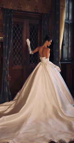 a woman in a white wedding dress is standing near a door with her hands on her hips