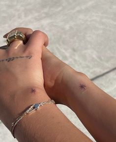 two people holding hands with tattoos on their arms and wrist, one has a gold ring