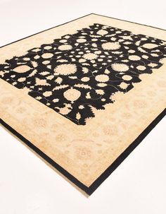 a black and beige area rug with an intricate design on the center, in front of a white background