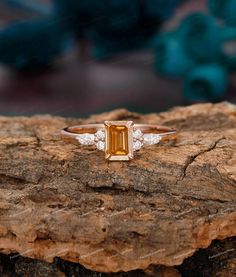 an emerald and diamond ring sitting on top of a rock