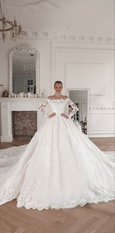 a woman in a white wedding dress standing on a wooden floor next to a fireplace