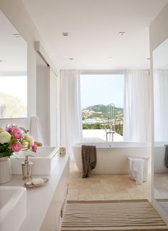 a bathroom with a tub, sink and large window looking out onto the outdoors area