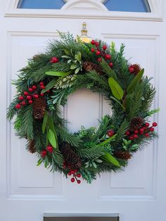 a christmas wreath on the front door of a house with red berries and greenery