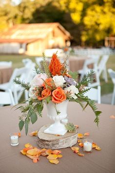 a vase filled with flowers sitting on top of a table covered in leaves and candles