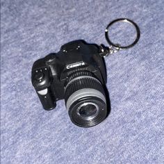 a camera keychain with a lens attached to it on a blue blanketed surface