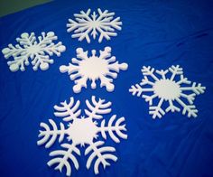 five snowflakes sitting on top of a blue tablecloth covered in white frosting