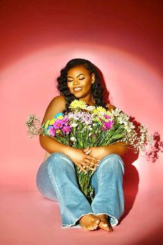 a woman sitting on the ground holding flowers