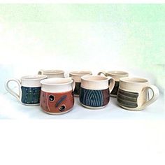 a group of coffee cups sitting next to each other on top of a white table