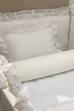 a crib with white sheets and pillows on it